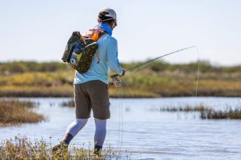 A man is standing in the water with a fishing rod.