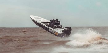 A boat with two people jumping out of the water.