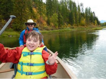 A man and a boy in a canoe on a river.