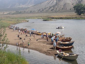 A group of people standing on the shore of a river.