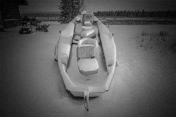 A black and white photo of a boat in the snow.