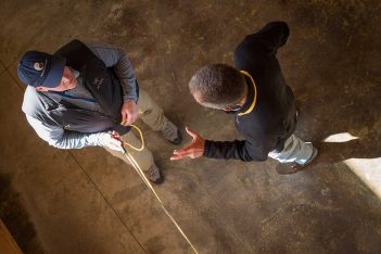 Two men standing in a room with a rope.