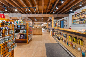 A well-lit store interior with wooden shelves displaying various merchandise, including brochures and souvenirs. A counter with information materials is on the right.