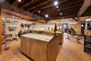 A wooden-paneled shop interior with display cases of small items, backpacks on the walls, and a variety of outdoor gear.