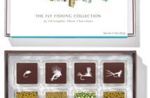 A box of chocolates labeled "The Fly Fishing Collection" by Christopher Elbow Chocolates, featuring chocolates with colorful fly fishing designs.