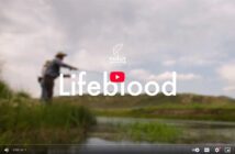 Person fishing in a grassy area near a river, with the words "Lifeblood" and "Trout Unlimited" overlaid on the image.