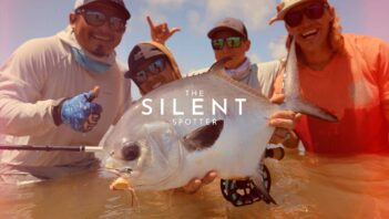 Four people holding a large fish and posing for the camera, wearing hats and sunglasses with the text "The Silent Spotter" overlaid on the image.